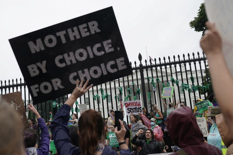 Women's March activists hold signs outside the White House following the Supreme Court's decision to overturn the landmark abortion decision