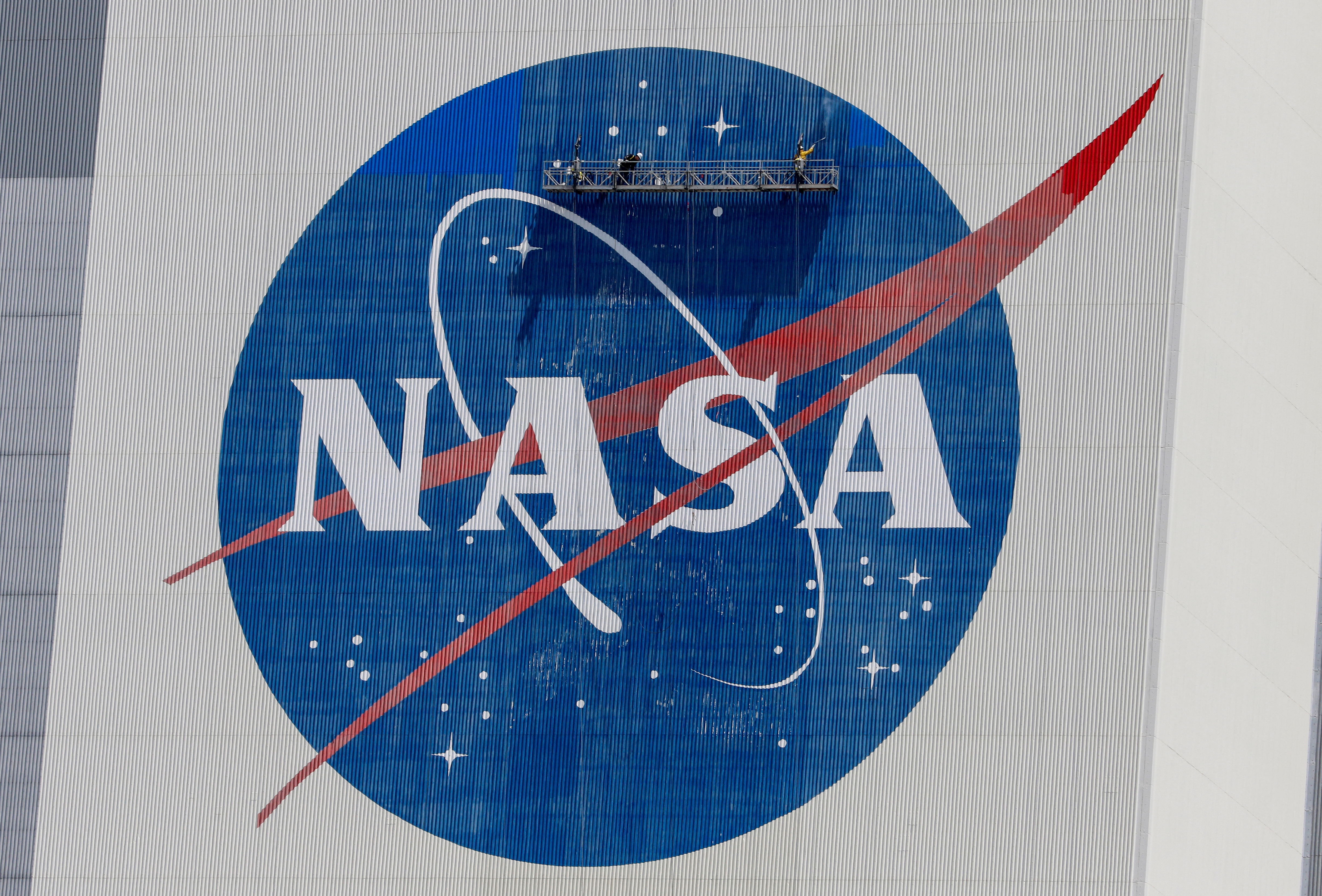 FILE PHOTO: Workers pressure wash the logo of NASA on the Vehicle Assembly Building before SpaceX will send two NASA astronauts to the International Space Station aboard its Falcon 9 rocket, at the Kennedy Space Center in Cape Canaveral, Florida, US, May 19, 2020 REUTERS/Joe Skipper/File Photo